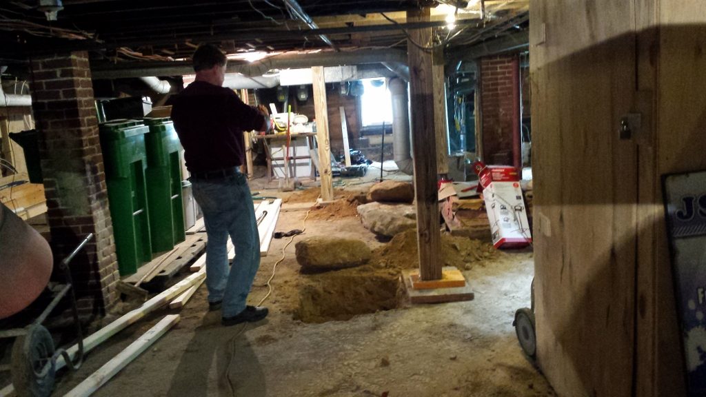 A man standing in the middle of an unfinished basement.