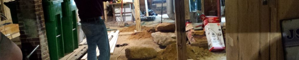 A man standing in the middle of an unfinished basement.