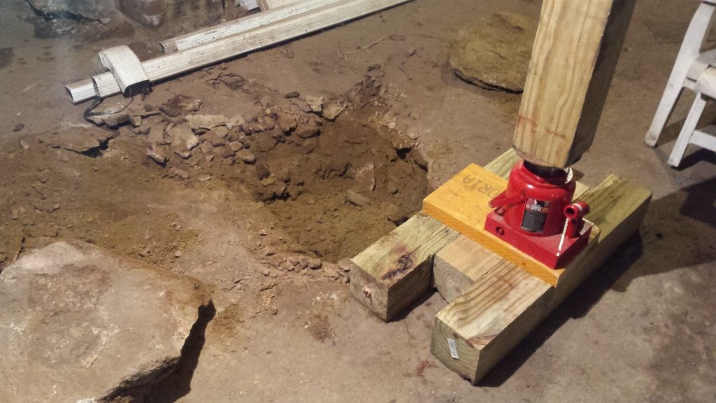 A hole in the ground with a piece of wood and a red object.